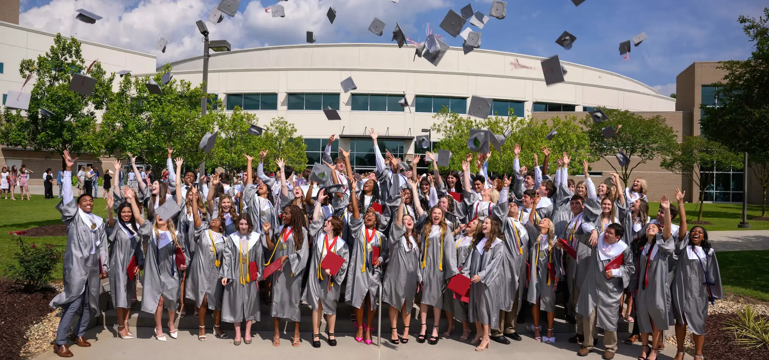 Dunham graduates tossing their caps after graduation.