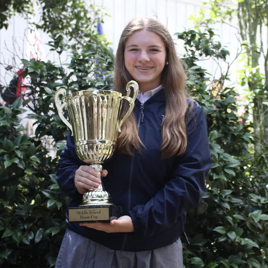 Middle School House captain holding the house cup trophy.