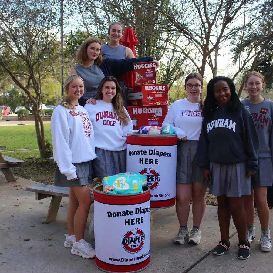 A group of Dunham high school girls standing beside items they have collected for those in need in the Baton Rouge community