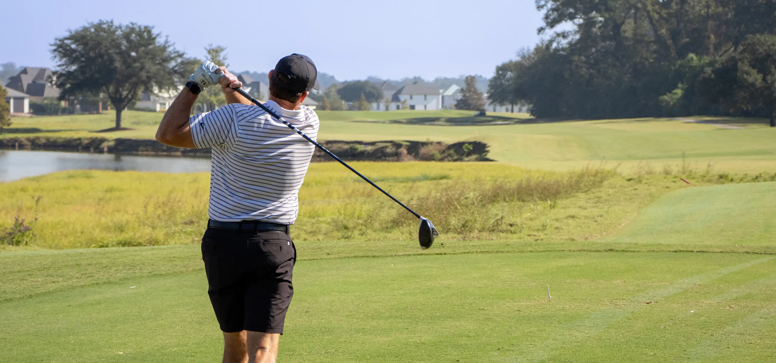 Golfer swinging club on tee box at Dunham Cup Golf Classic