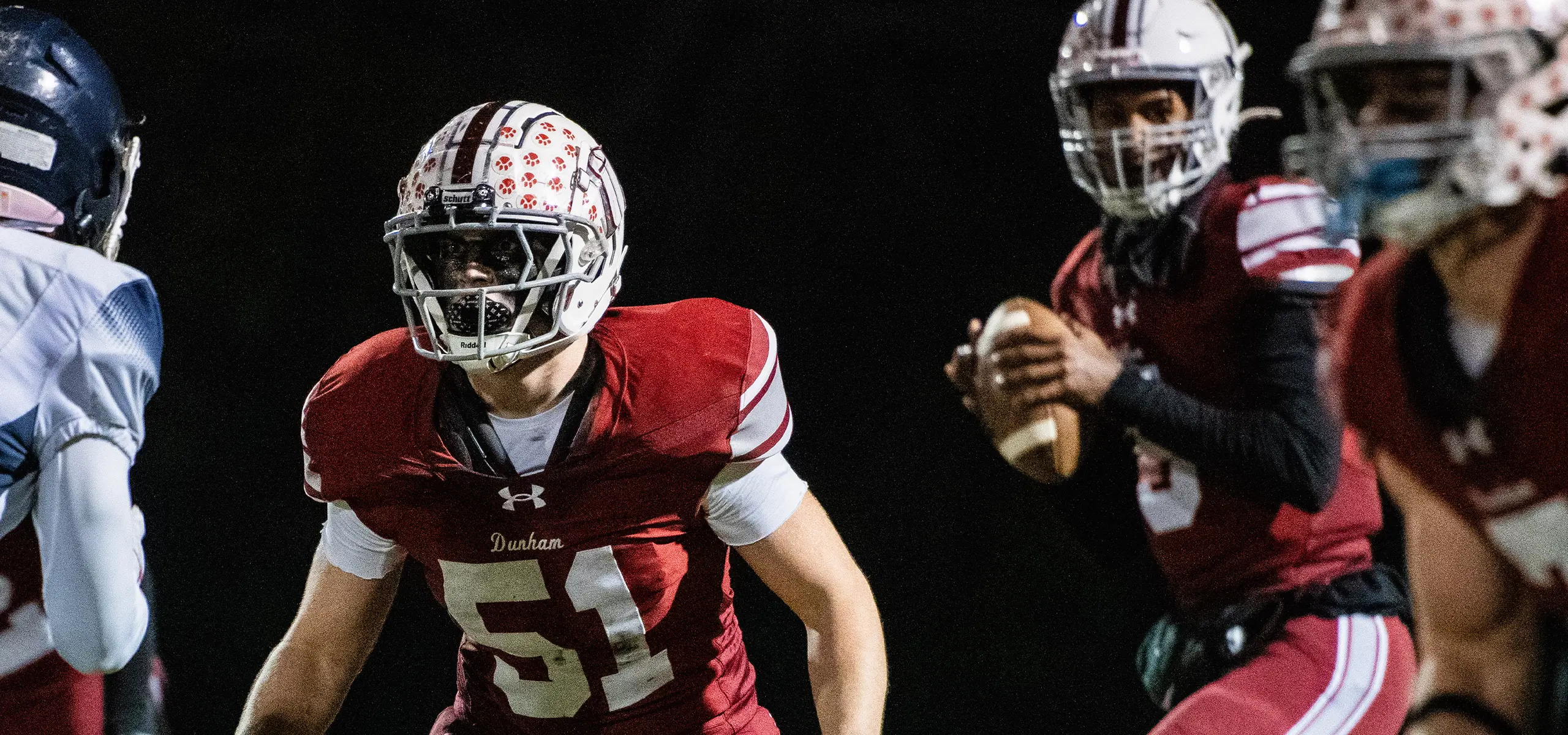 Three Dunham football players executing a play.