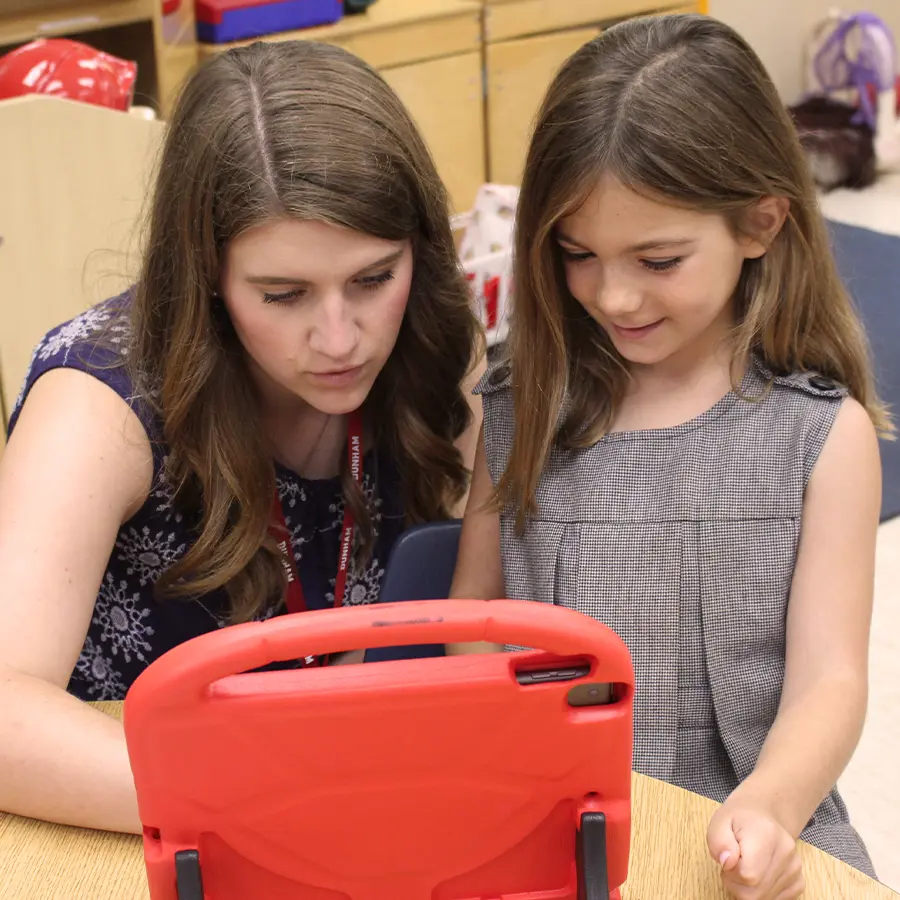 Lower school teacher instructing lower school student with iPad.